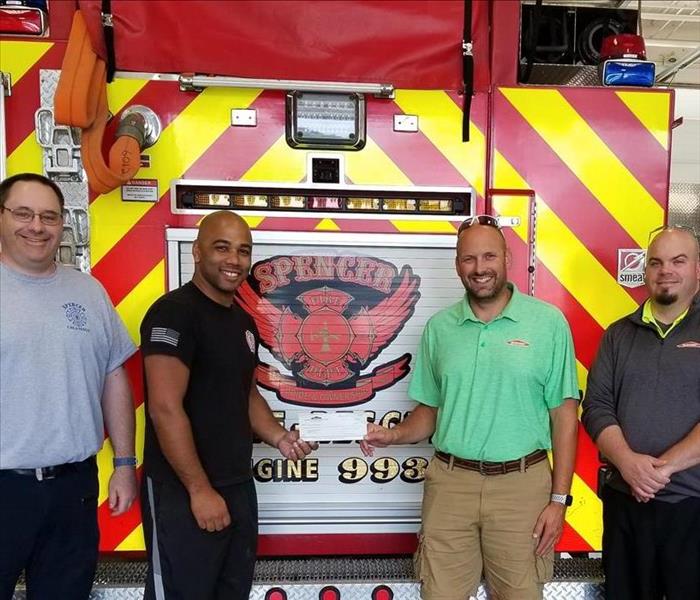 Photo of Owner Ryan Brooks and Sales and Marketing Manager Jason Lindsay presenting a check to the Spencer Fire Department